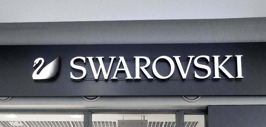 Białe litery 3D z podświetleniem LED zamontowane na czarnym tle szyldu sklepowego, tworzące kontrastowy i nowoczesny efekt wizualny.