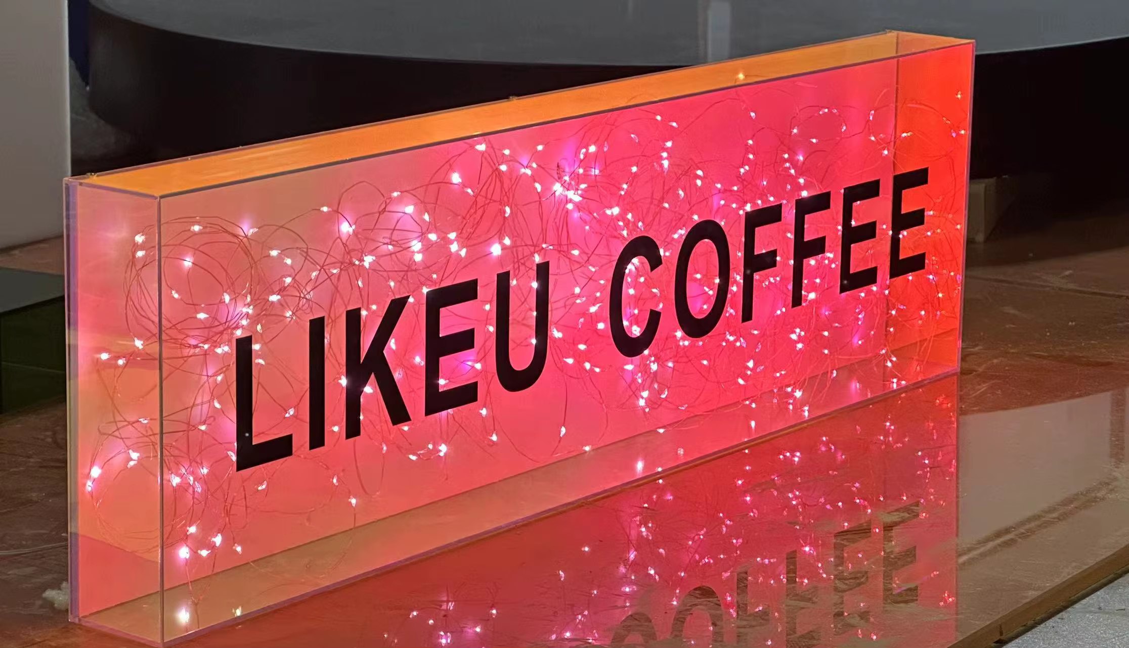 Przezroczysty kaseton świetlny z plexi z dekoracyjnym oświetleniem LED przypominającym girlandę, tworzący efekt nowoczesnej, nastrojowej reklamy.