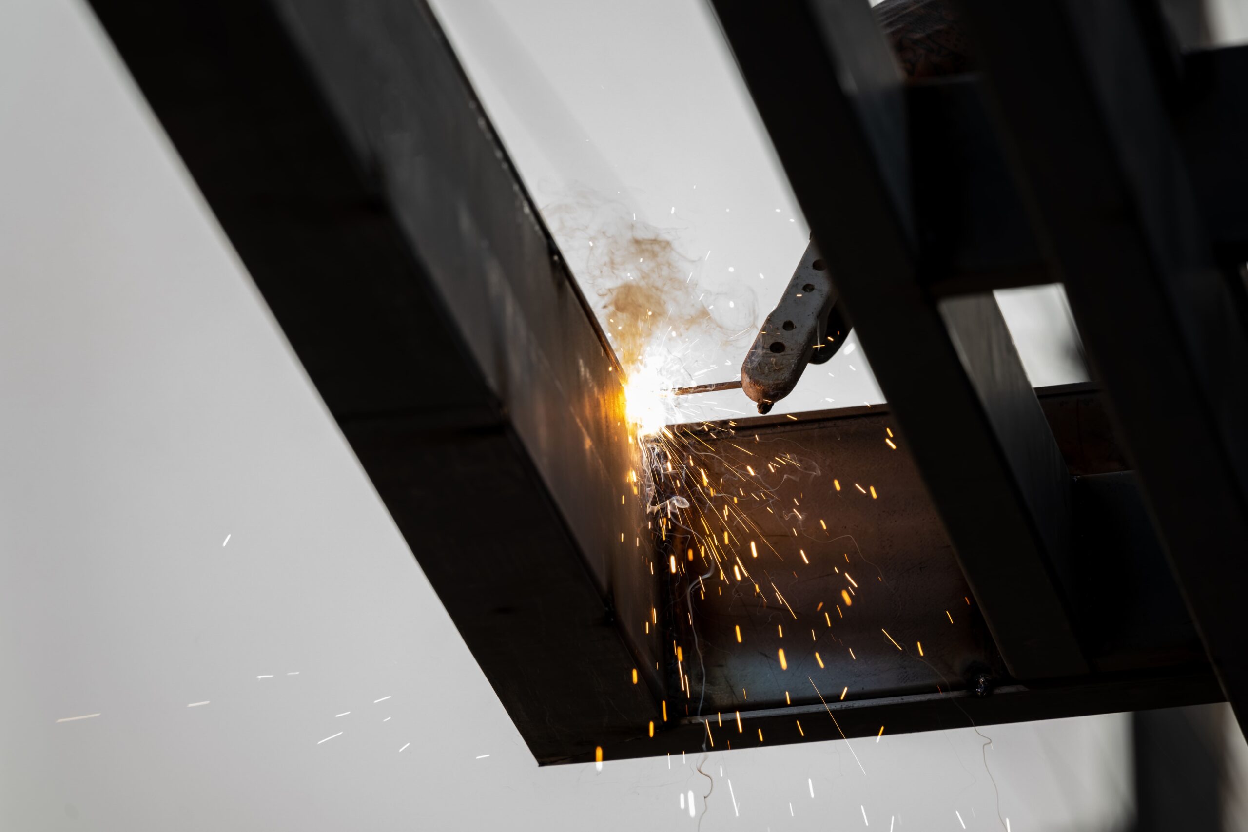 Proces spawania stali łukiem elektrycznym z widocznymi iskrami.