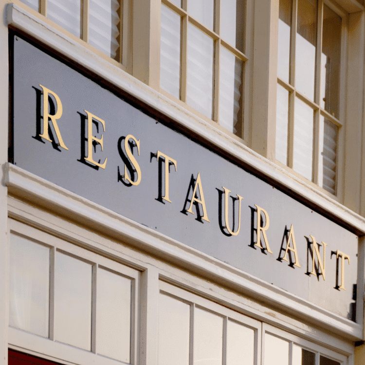 Złote litery 3D zamontowane na czarnym tle szyldu restauracji, tworzące elegancki i klasyczny efekt wizualny.