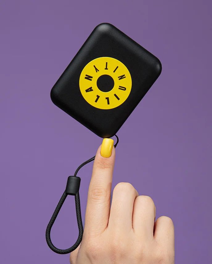 Małe czarne etui z motywem Illan Unity balansujące na palcu.