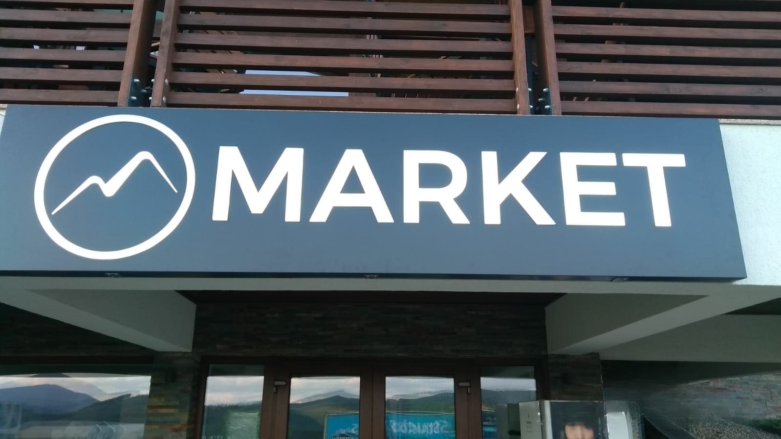 Realizacja szyldu dla sklepu MARKET — nowoczesny kaseton wykonany z odpornego na warunki atmosferyczne dibondu, z literami 3D podświetlanymi energooszczędnym oświetleniem LED.